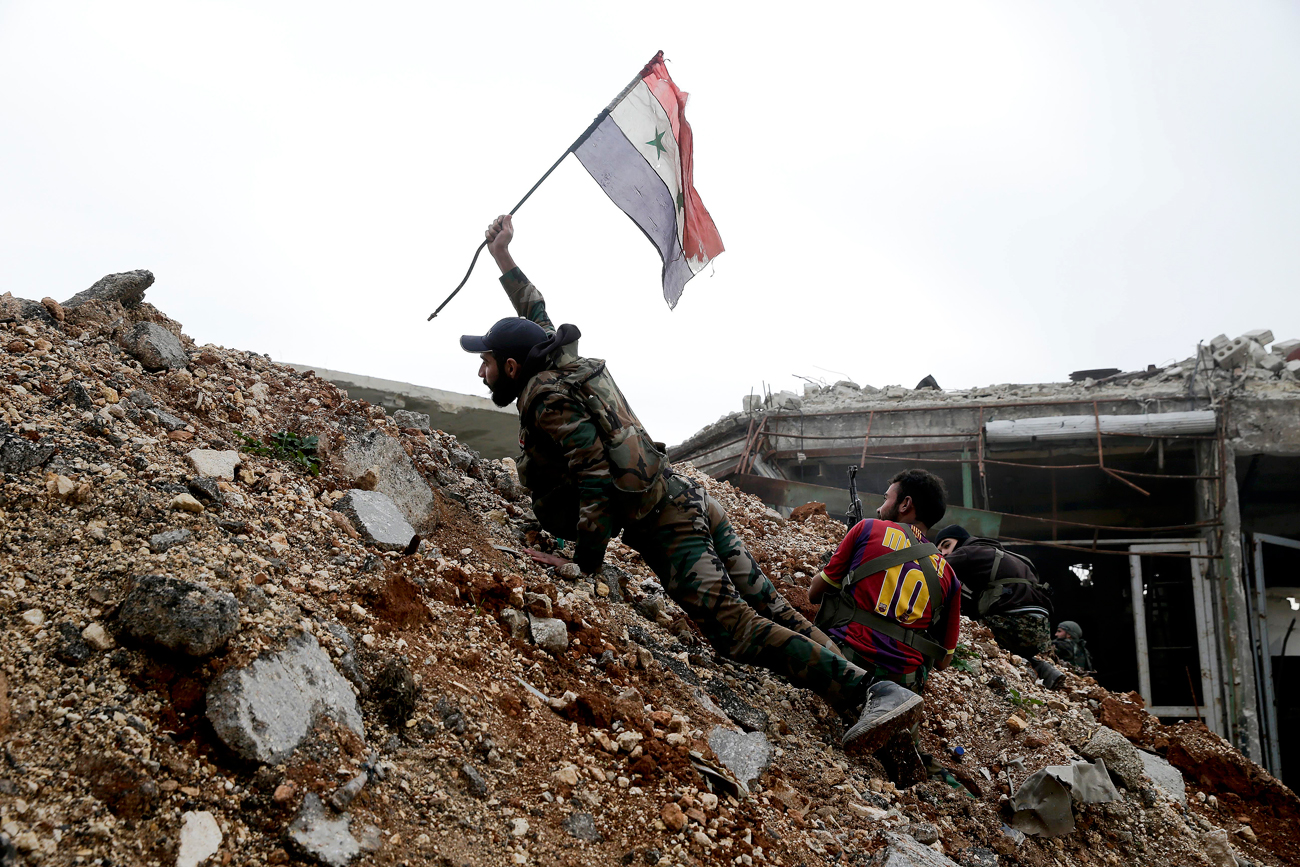 A Syrian army soldier places a Syrian national flag during a battle with rebel fighters at the Ramouseh front line, east of Aleppo, Syria.