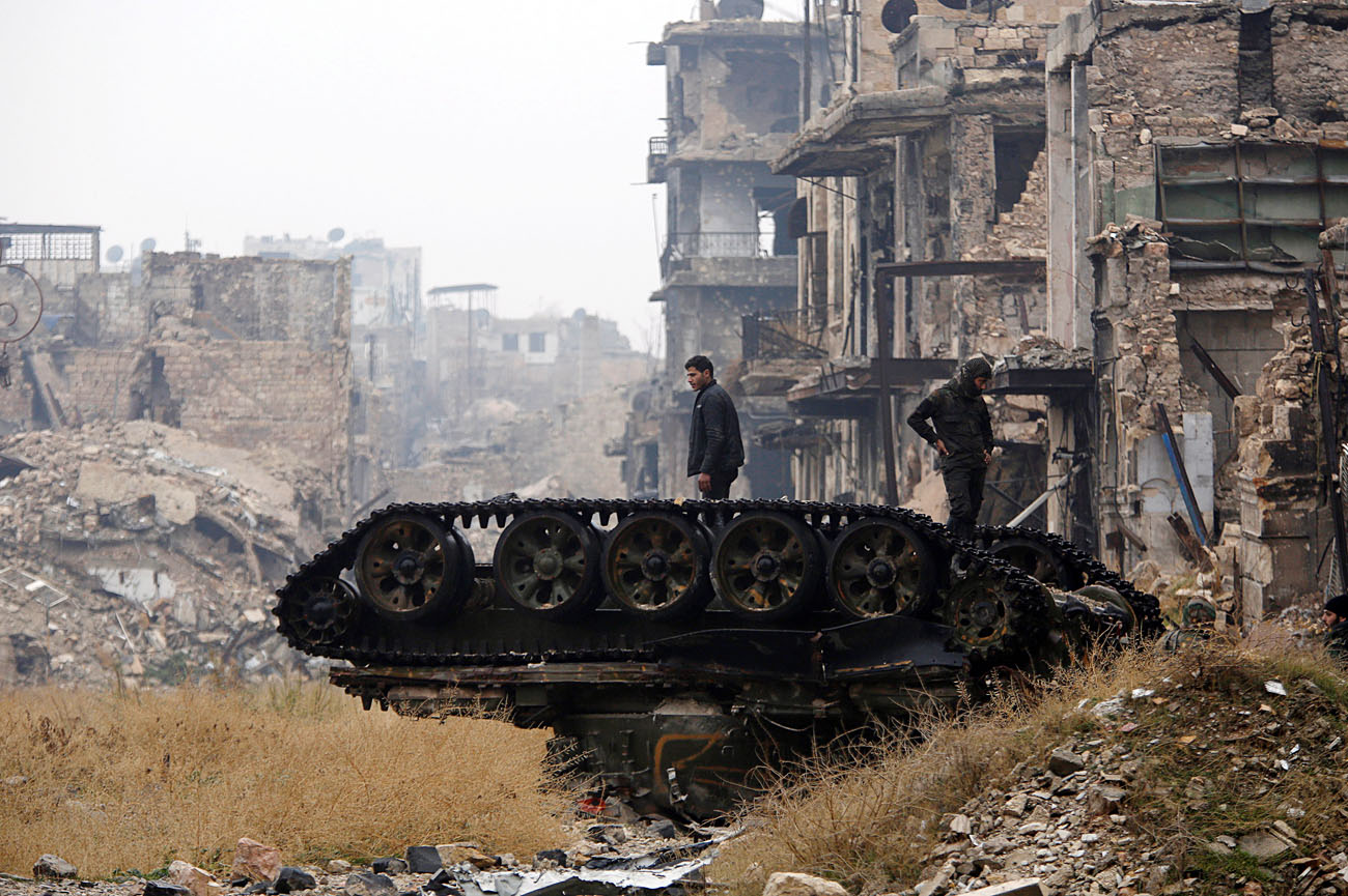 Dua orang prajurit dari pasukan yang setia kepada Presiden Bashar al-Assad berdiri di atas tank yang hancur di dekar masjid Umayyad di wilayah Aleppo yang dikuasai pemerintah, 13 Desember 2016.
