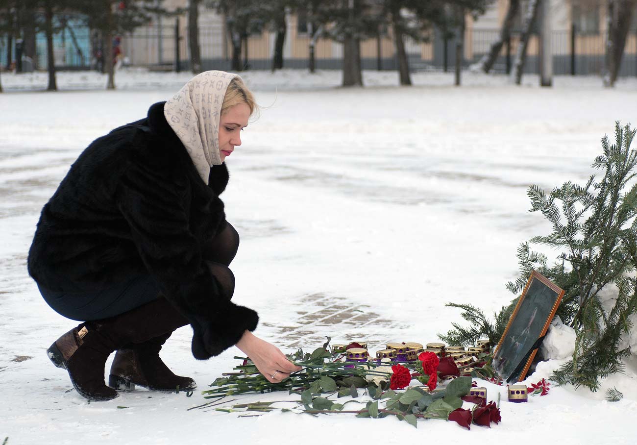 Una ragazza depone dei fiori davanti alla foto di una delle vittime del Tu-154 precipitato nel Mar Nero. 