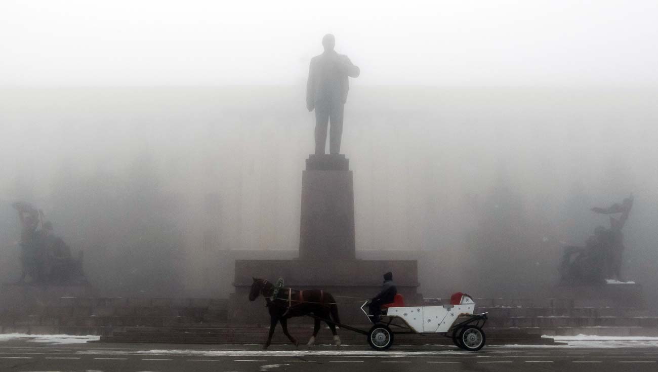 Човек во коњска кола поминува низ магла покрај споменикот на основачот на Советскиот Сојуз Владимир Илич Ленин на централниот плоштад во Ставропол, јужна Русија