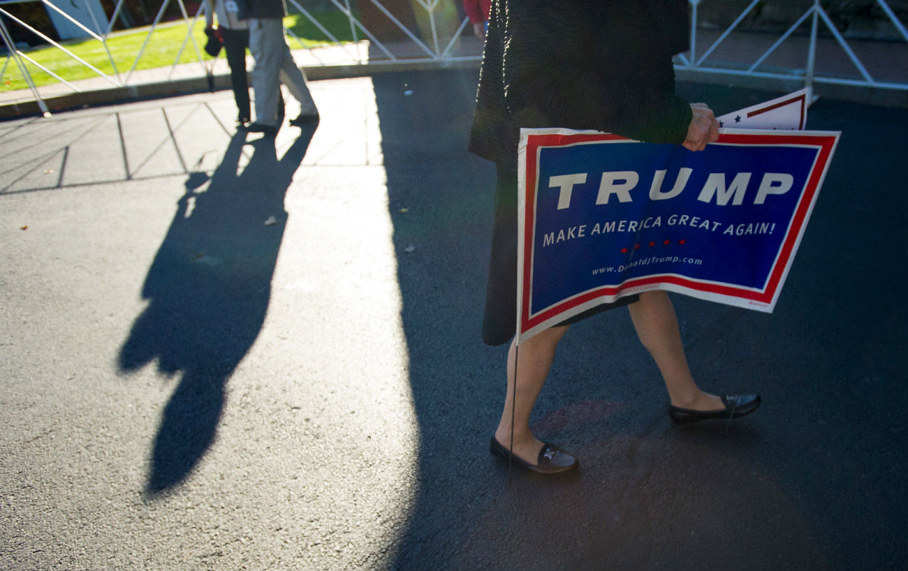A woman carries a sign for U.S. Republican presidential candidate Donald Trump following a campaign event in Atkinson, New Hampshire, Oct. 26, 2015