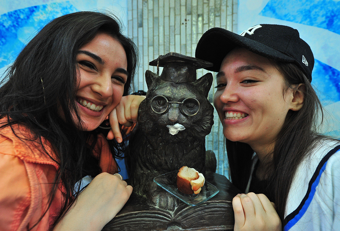 Due studentesse insieme alla statua del gatto portafortuna all'Università Rudn di Mosca.
