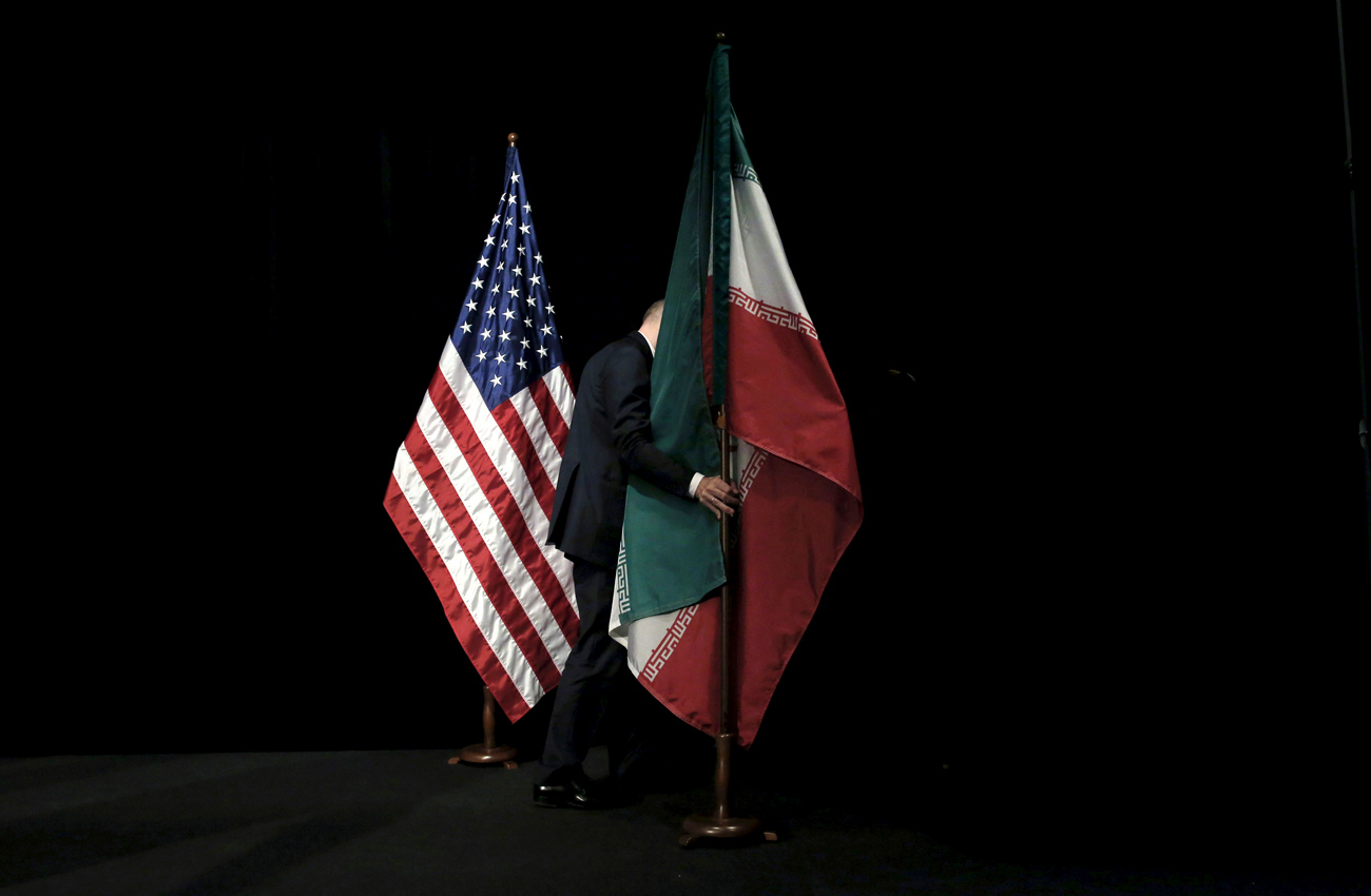 Experts say that Russia may not join U.S. efforts to contain Iran, despite the formal improvement of Russian-U.S. relations. Photo:  A staff member removes the Iranian flag from the stage after a group picture with foreign representatives during the Iran nuclear talks at the Vienna International Center.