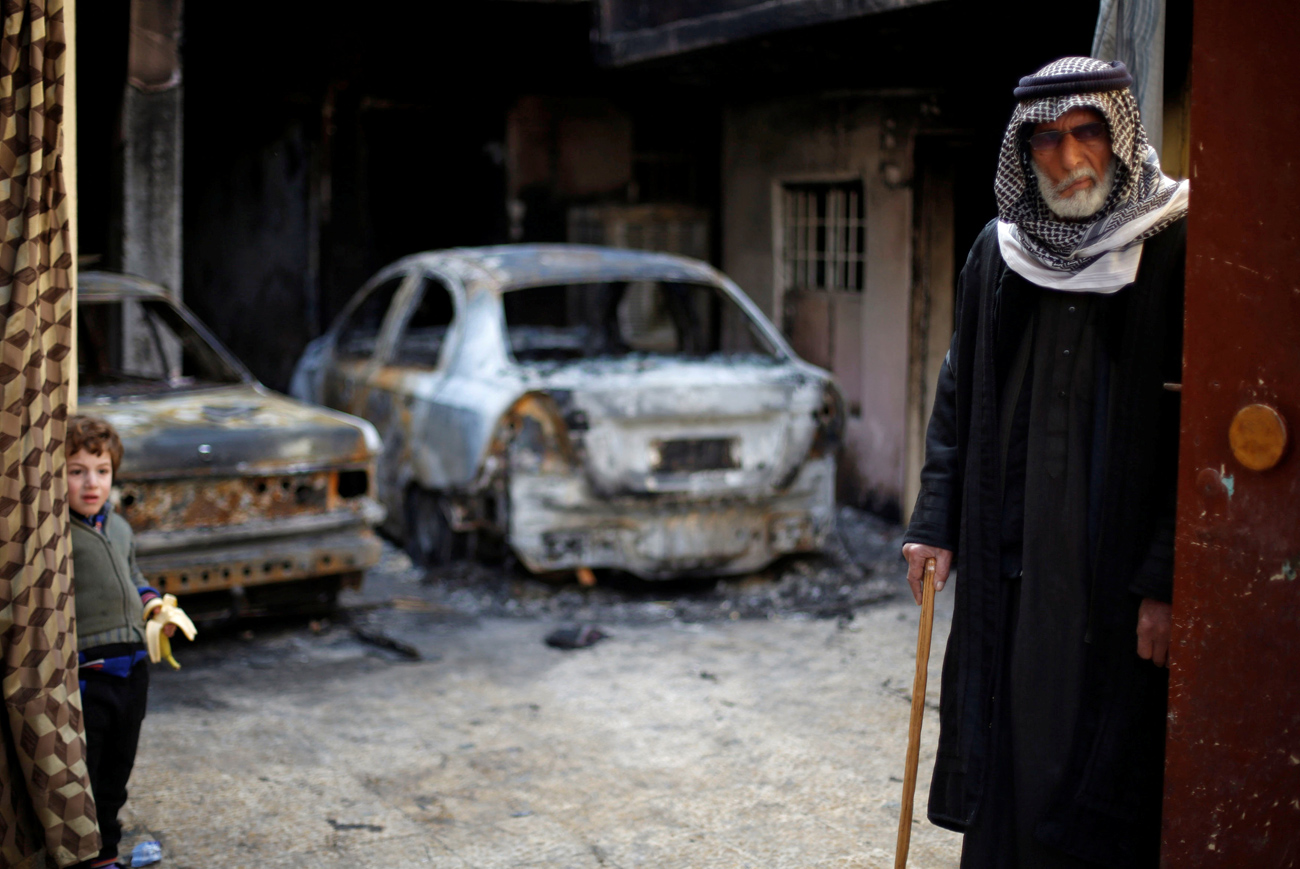Homem e criança em frente a casa incendiada por EI fotografados minutos antes de deixar Mossul 