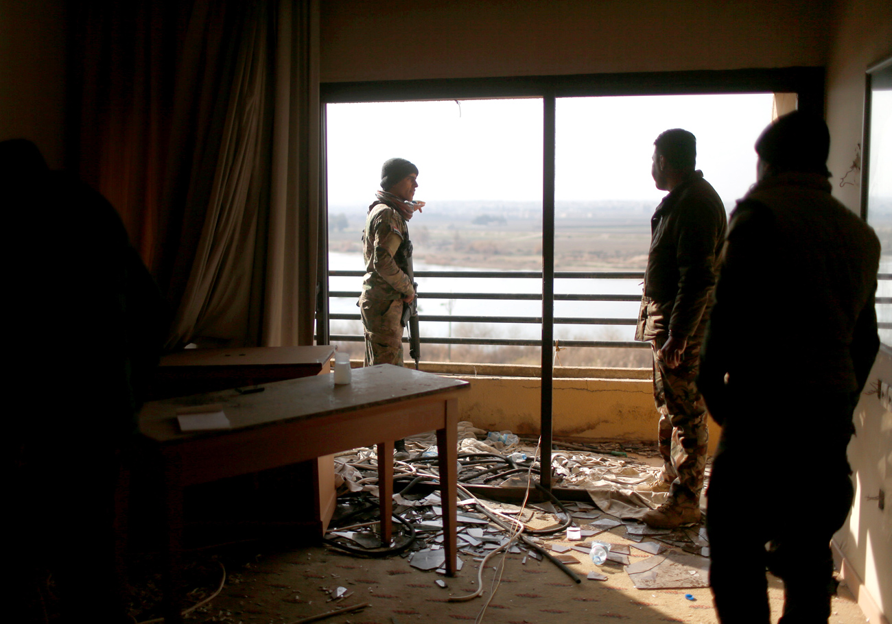 Iraqi soldiers look out from a damaged room in the five-star Ninewah Oberoi Hotel in Mosul city, Mosul, Iraq. 