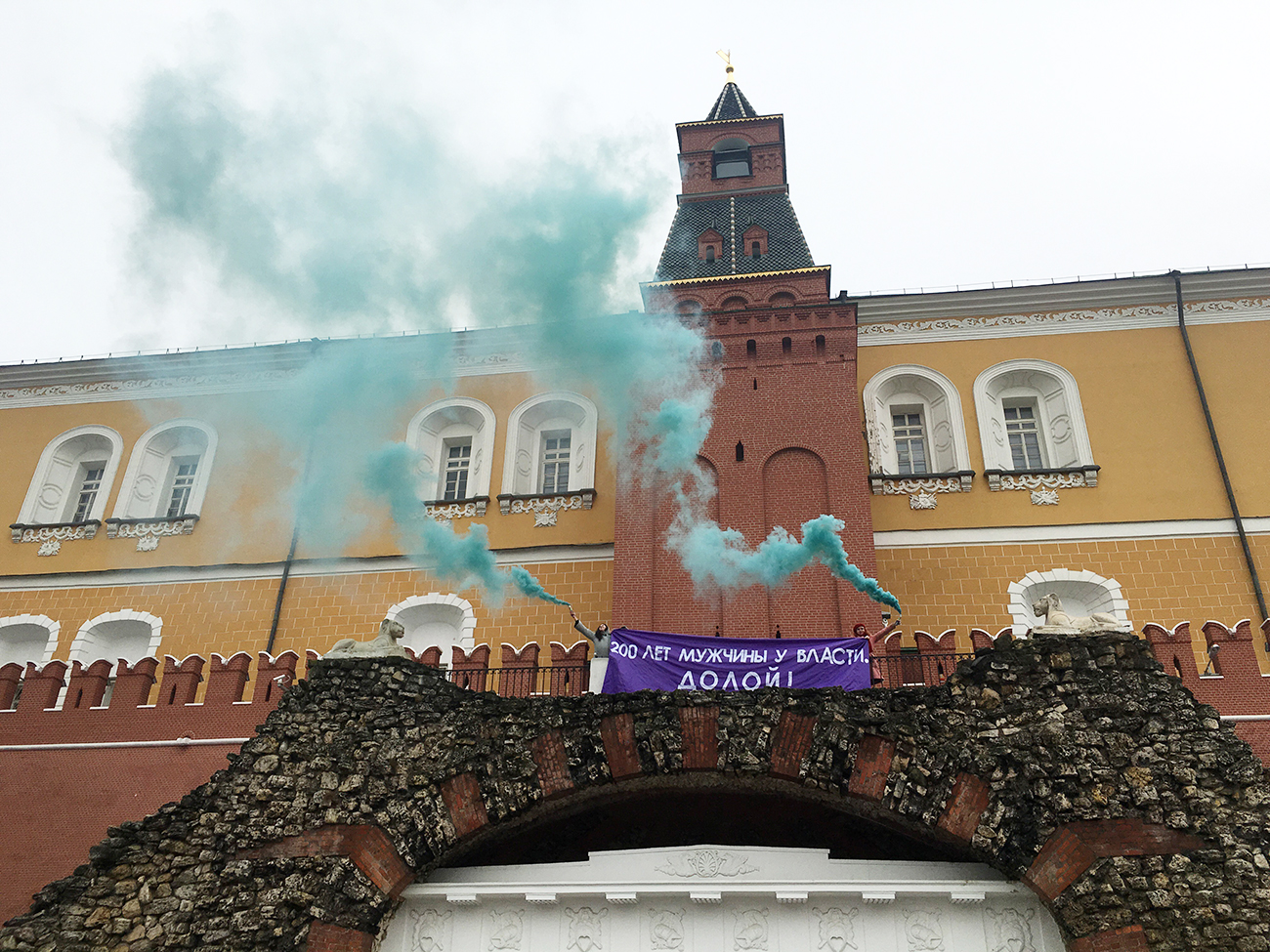 MOSCOW, RUSSIA - MARCH 8, 2017: Feminist activists unfurl a banner with a message reading "Men have been in power for 200 years. Down with it!" and light smoke flares outside the Kremlin on the International Women's Day