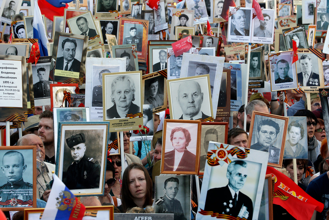 5月9日、ロシアの多くの街で、戦争に参加した親族の写真を持ちながら、数千人の人々が通りを歩く。＝