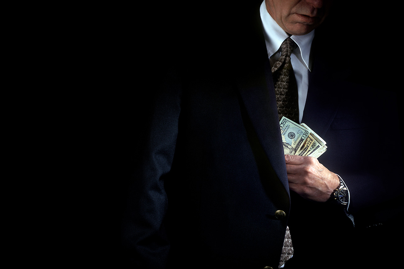 Mature businessman hiding money in his pocket
