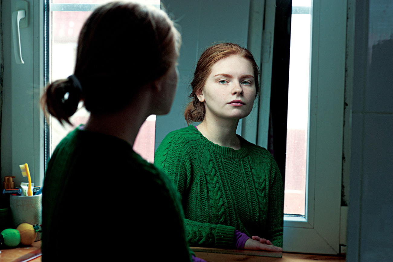 Beautiful red-haired girl looking at the mirror. Russia