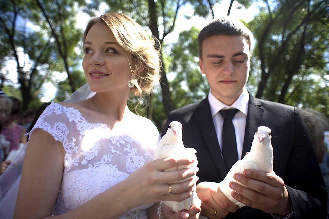  JULY 8, 2014. A newly wedded couple holds white doves in their hands at the unveiling ceremony of a monument dedicated to Saint Peter and Saint Fevronia, Orthodox patrons of fidelity, family and love. The event took place near the church of the Trinity church in Trinity-St. Sergius Lavra (monastery) in Sergiyev Posad. 