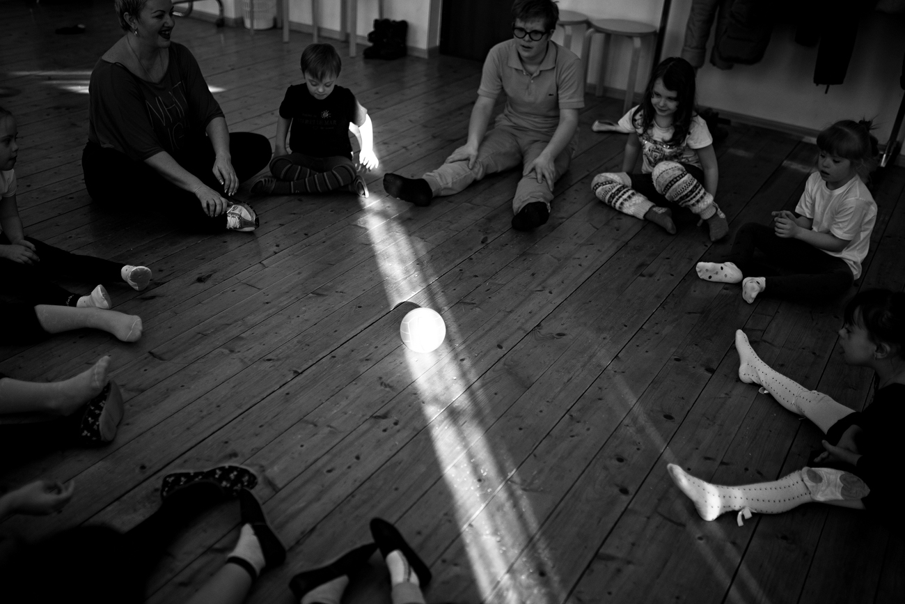 As crianças fazem um círculo no chão e rolam uma bola entre si - é assim que elas aprendem, aos poucos, a se comunicar no centro aberto por Kaiukova.