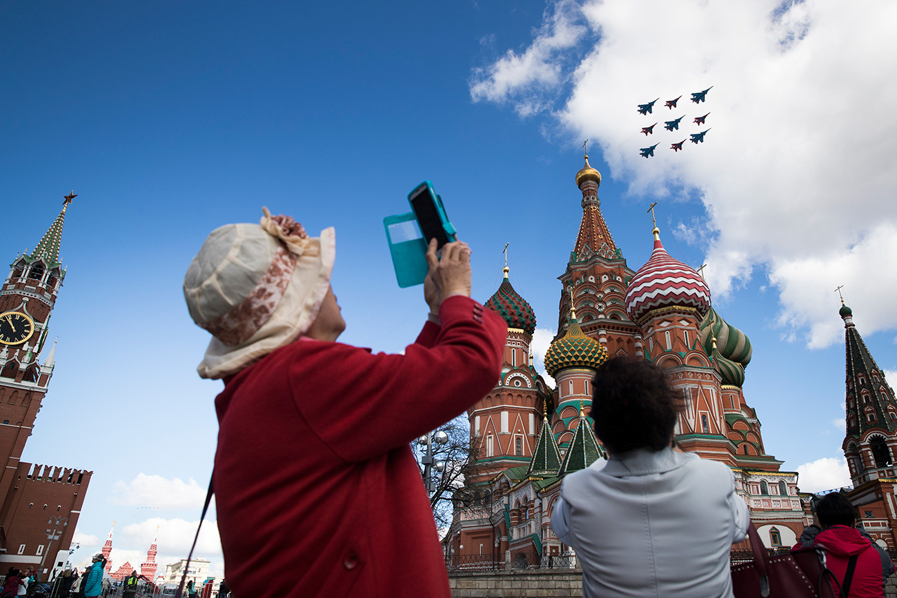 Wisatawan mengambil foto jet-jet tempur Rusia yang terbang melintasi Kremlin.