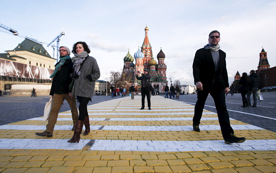 People walk along a road surface marking which is painted on the stone-block pavement of Red Square, with St. Basil's Cathedral and the Kremlin wall (R) seen in the background, in central Moscow April 17, 2015.