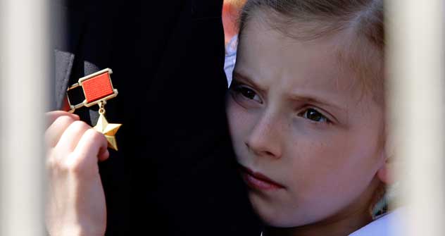 Verbundenheit der Generationen: Die Enkelin eines Veteranen umarmt ihren Großvater und zupft an  seinem „Held der Sowjetunion“-Orden, der einst höchsten Auszeichnung des Landes. Foto: AFP/Eastnews