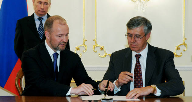 Russian Prime Minister Vladimir Putin, background, at the signing ceremony for documents specifying agreement on strategic cooperation between Rosneft and ExxonMobil at Novo-Ogaryovo, April 16, 2012. Foreground, from left: United Shipbuilding Corpora