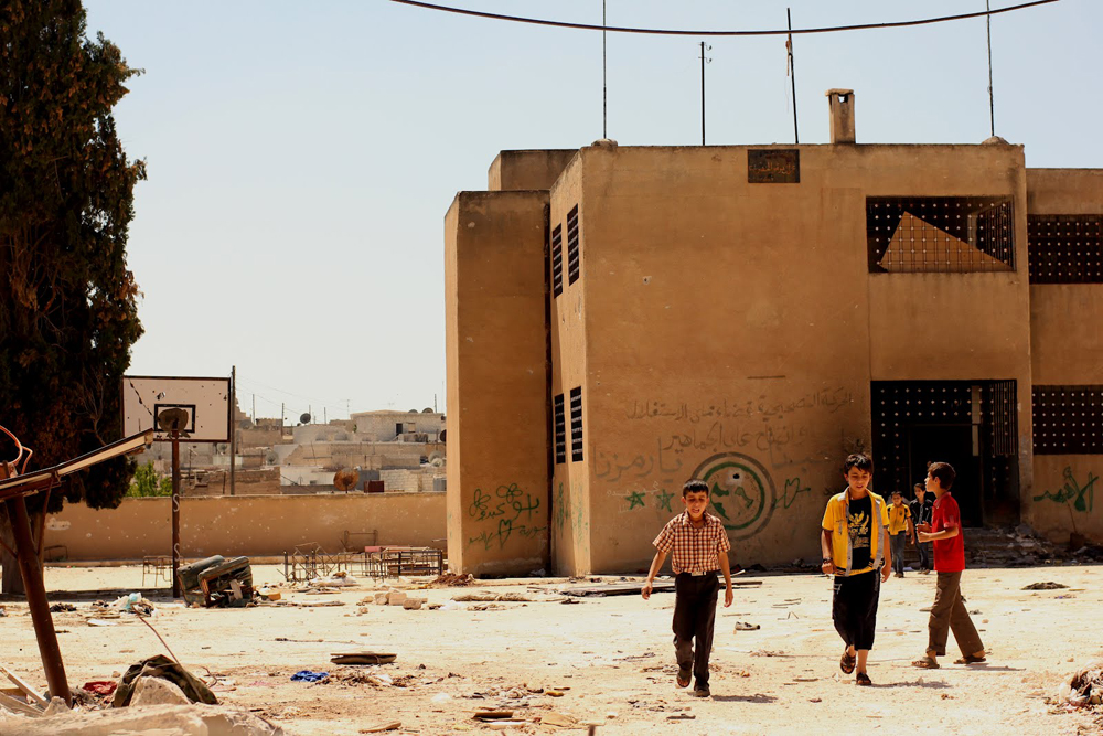 The main problem of the camps of refugees is the lack of water, a problem with the same repetitive diet, and suffocating boredom. Pictured: Children walk round the playground of their old school in Azaz, 50km north of Aleppo. Source: Spike Rogers, Al