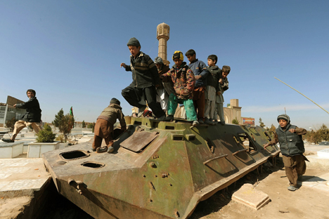 Crianças brincam sobre restos de tanque soviético em Herat, no oeste do Afeganistão Foto: AFP / East News
