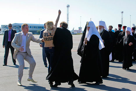 An activist from Ukrainian women's rights group FEMEN performs an act of protest against the Russian Orthodox Patriarch Kirill upon his arrival at the Kiev airport on July 26, 2012. Source: AFP