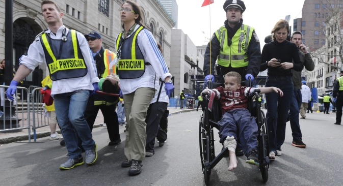 A Boston police officer wheels in injured boy down Boylston Street as medical workers carry an injured runner following an explosion during the 2013 Boston Marathon in Boston, Monday, April 15, 2013. Source: AP