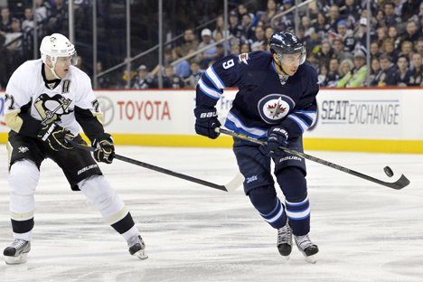 Winnipeg Jets' Evander Kane (R) tries to control a bouncing puck as he skates past Pittsburgh Penguins' Evgeni Malkin during the second period of their NHL hockey game in Winnipeg, on February 15. Source: Reuters / Fred Greenslade