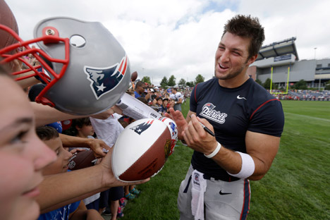 New England Patriots quarterback Tim Tebow, right, signs autographs for fans following an NFL football practice in Foxborough, July 28, 2013. Source: AP 