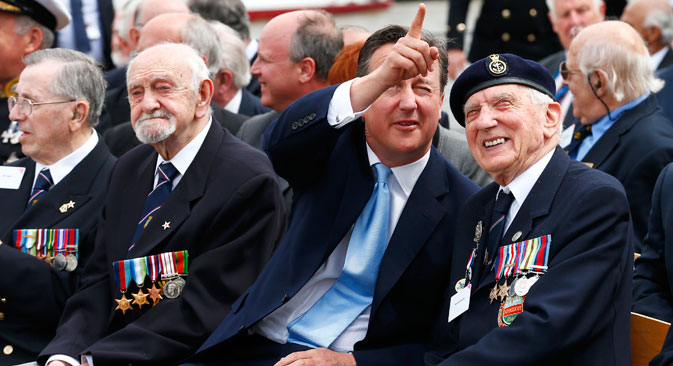 Britain's Prime Minister David Cameron points as he chats to D-Day veteran Kenneth Sturdy during an event on the deck of battleship HMS Belfast in central London, May 20, 2014. Source: Reuters