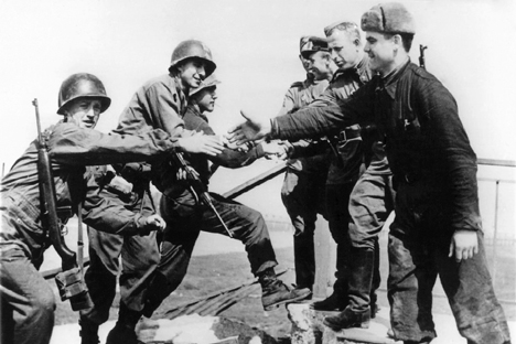 American (left) and Russian soldiers shake hands on April 24, 1945 at the destroyed bridge over river Elbe as both troops meet at Torgau, Germany. 