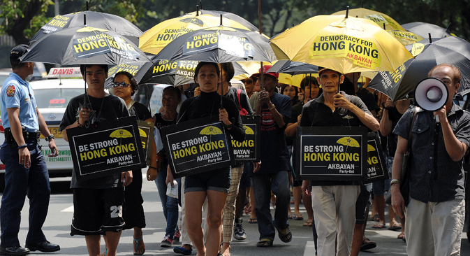 Filipino activists carrying umbrellas painted with slogans, march towards the Chinese consular office to show their support for Hong Kong pro-democracy protesters during a rally in the financial district of Manila on October 2, 2014. Source: AFP / East NEws