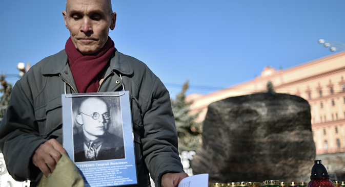 A man holds his father's portrait near the memorial to the victims of Soviet-era political repression, the Solovky Stone monument, on Lubyanka Square in Moscow, on October 29, 2014. Source: AFP / East News