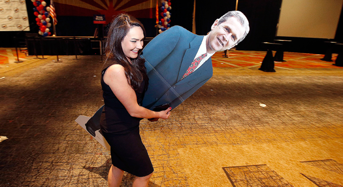 Katie Granger leaves the Republican election night festivities party with a photo cutout of former President George W. Bush, Tuesday, Nov. 4, 2014, in Phoenix. Source: AP