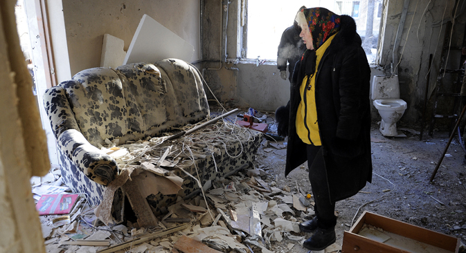 A local resident surveys damage to her flat in a block of flats in the aftermath of a shelling attack on Donetsk, on Jan. 8. Source: Khudoteply Aleksandr / TASS