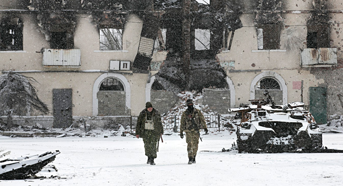 Fighters of the self-proclaimed Donetsk People's Republic walk past a destroyed Ukrainian army armoured personnel carrier in the town of Vuhlehirsk, about 10 km (6 miles) to the west of Debaltsevo, Feb. 16. Source: Reuters