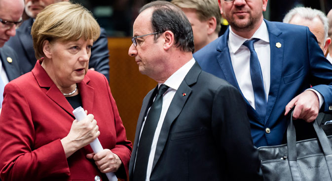 German Chancellor Angela Merkel, left, speaks with French President Francois Hollande, center, during a round table meeting at an EU summit in Brussels on Thursday, March 19, 2015. Source: AP