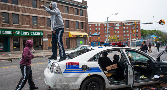 A protestor stands on a destroyed Baltimore City Police car on North Avenue during a protest for the death of Freddie Gray in Baltimore, Maryland, USA, 27 April 2015. Source: EPA