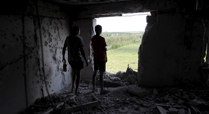 Local residents look through a hole in a damaged multi-story building, which according to locals was caused by recent shelling, in Avdeyevka, Donetsk Region, July 18, 2015. Source: Reuters