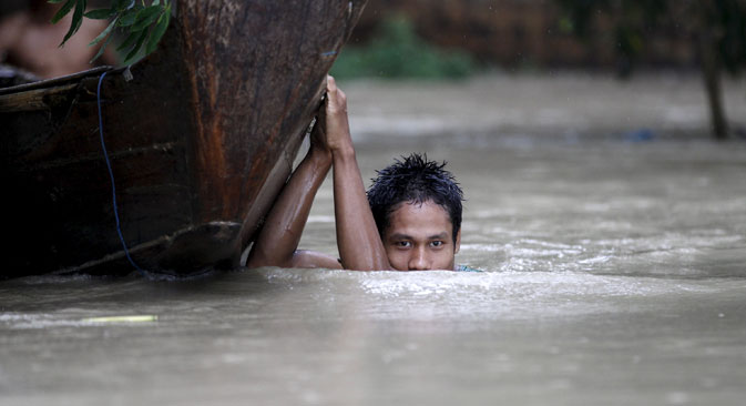 A boy moves his boat in a flooded village outside Zalun Township, Irrawaddy Delta, Myanmar, August 6, 2015. Source: Reuters