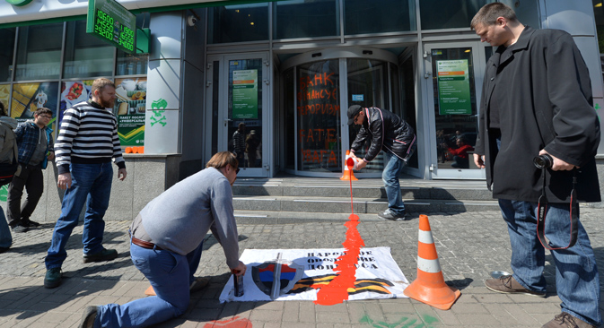 "Este banco financia el terrorismo", reza la pintada a la entrada del banco Sberbank, mientras varios activistas vierten pintura sobre un cartel. Fuente: AFP / East News