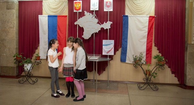 Escolares en una escuela de Crimea ante las banderas de Rusia y la península. Fuente: RIA Novosti.