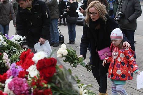 Des gens déposent des fleurs devant l'ambassade de France à Moscou.