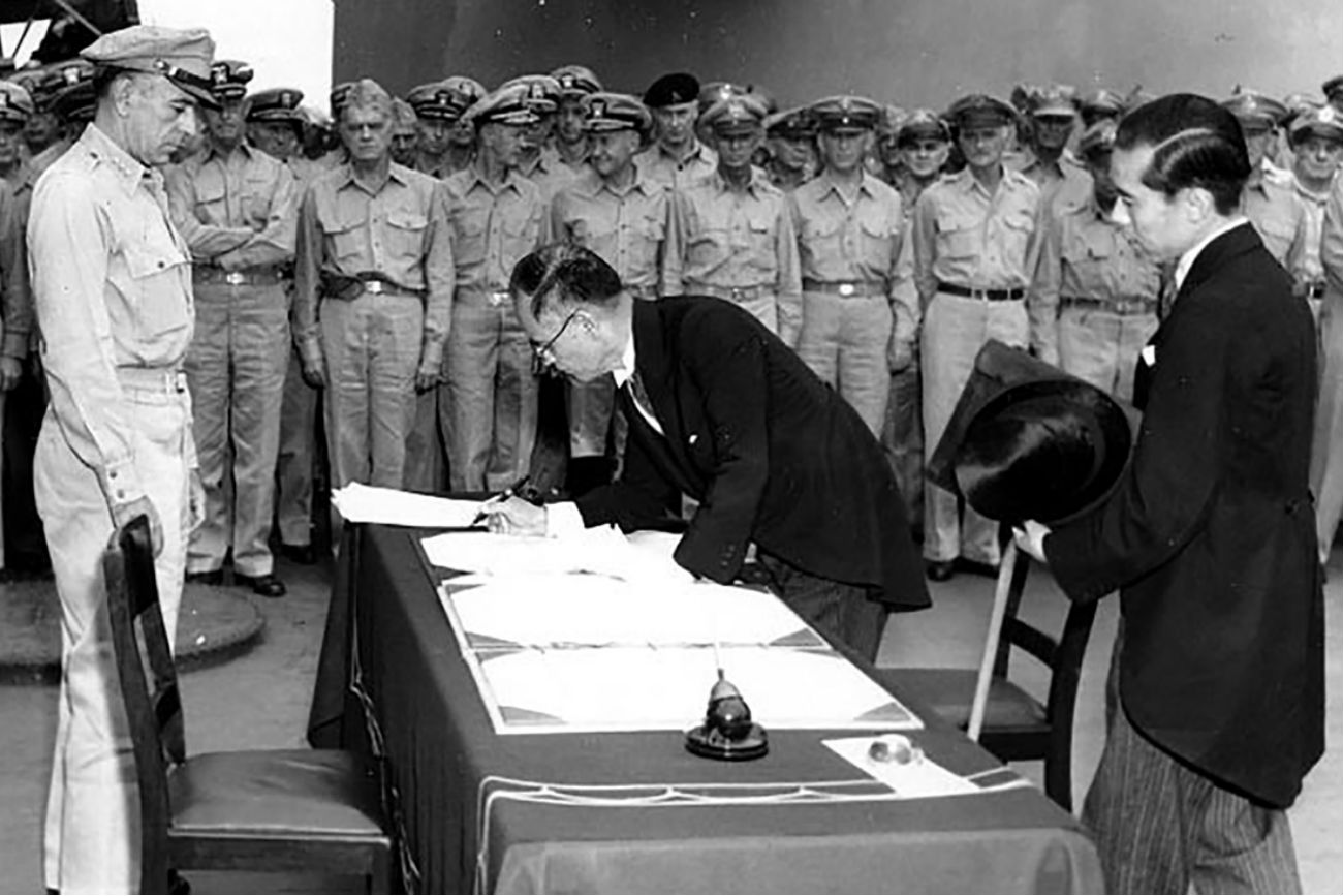 Japonski zunanji minister Mamoru Šigemitsu podpisuje dokument o predaji japonske na ladji USS Missouri. Opazuje ga general Richard K. Sutherland. 2. september 1945.