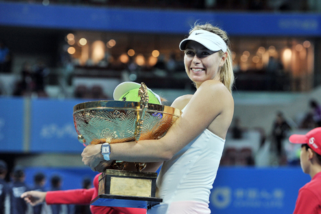 Maria Sharapova berpose sambil memegang trofi yang ia menangkan dalam pertandingan tenis tunggal wanita melawan Petra Kvitova dari Republik Ceko di Turnamen China Open, Beijing, 5 Oktober 2014. Foto: AFP/East News