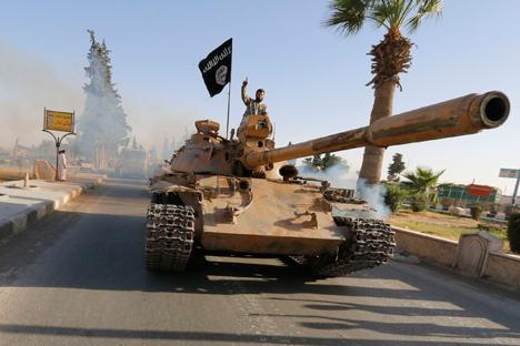 Para pejuang militan Islam di atas tank ikut serta parade militer di sepanjang jalan di utara Provinsi Raqqa pada 30 Juni 2014. Para pejuang Islam militan ini mengadakan parade untuk merayakan deklarasi mereka atas pembentukan "khilafah" Islam setelah kelompok ini ditangkap di wilayah negara tetangga mereka, Irak.