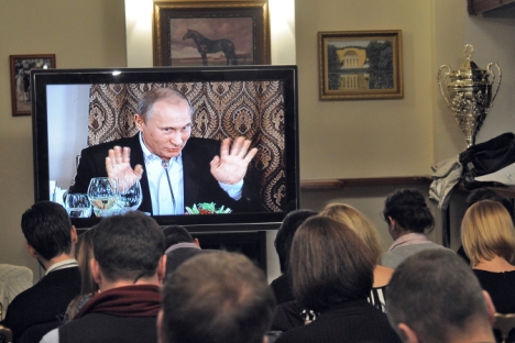 Vladimir Putin speaking from a TV screen during a Valdai club discussion. Source: Kommersant 