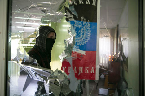 Masked man walks past a broken window inside the Mariupol town hall in east Ukraine April 26, 2014. Source: Reuters