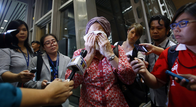 TV journalists try to interview a crying woman as she waits more information about the Malaysian Boeing 777 after it was shot down. Source: Reuters