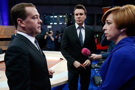 Russia's Prime Minister, Dmitry Medvedev, left, speaks during a live nation-wide TV show at Moscow's Ostankino TV center, Russia, Wednesday, Dec. 10, 2014. Mikhail Zygar of Dozhd, center, and Marianna Maksimovskaya of REN TV listen. Source: AP