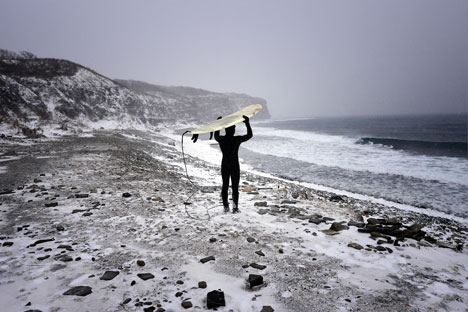 A man with his surfboard walking along the Ussuri Bay coast on Russky Island, Dec. 21, 2014. Source: Yuri Smityuk/TASS