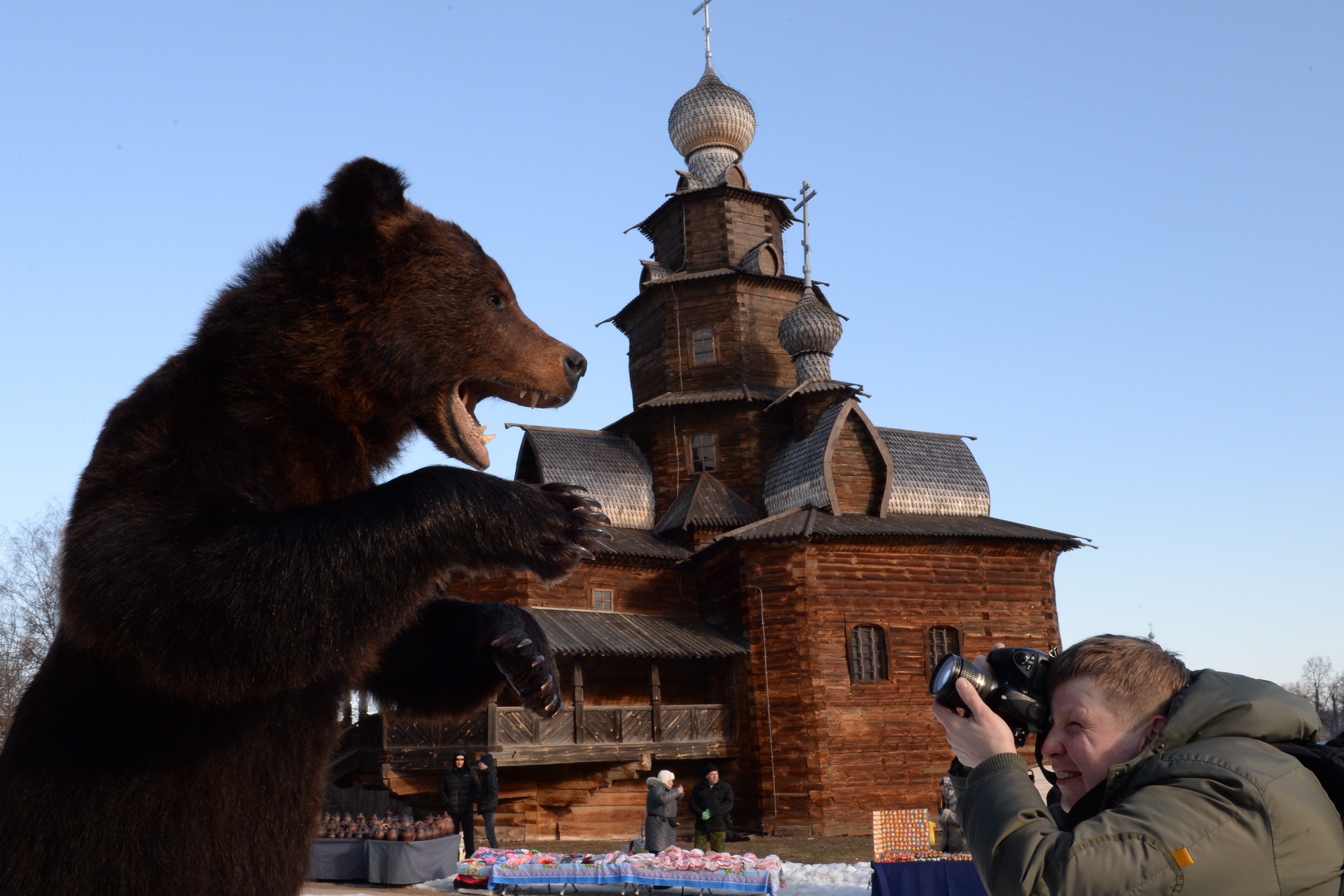 A man photographs a stuffed bear at the Museum of Wooden Architecture in Suzdal during Maslenitsa festivities.