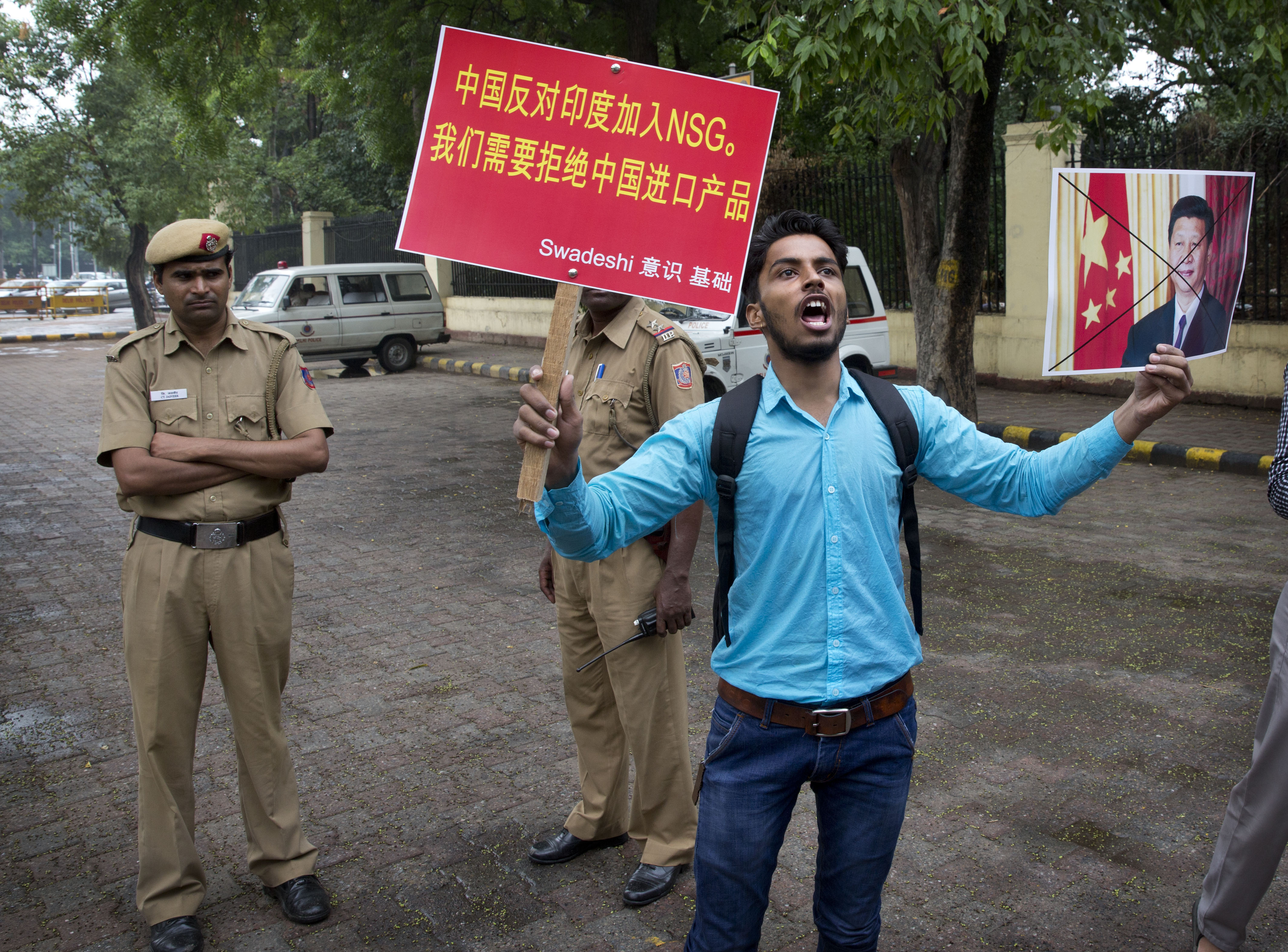 An activist holds a portrait of Chinese President Xi Jinping and shouts slogans during a protest near the Chinese embassy in New Delhi, June 28, 2016.