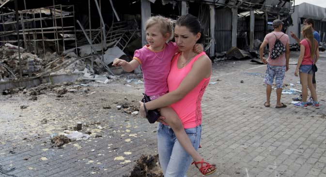 Continuano gli scontri nel Donbass. Una donna si allontana da un edificio distrutto con la figlia in braccio (Foto: Reuters)